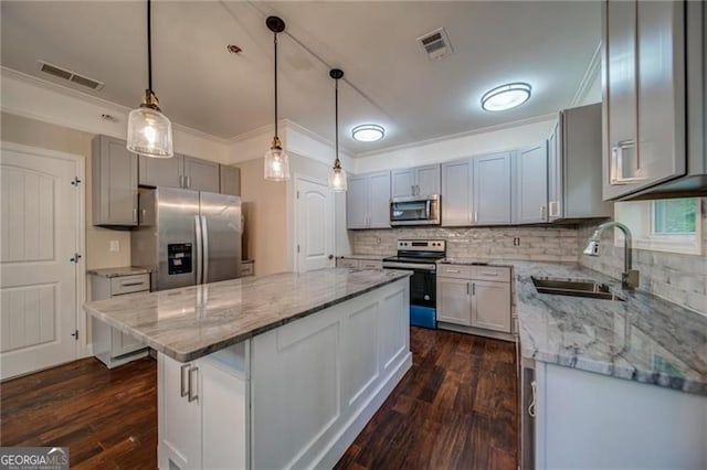 kitchen featuring sink, stainless steel appliances, dark hardwood / wood-style floors, decorative light fixtures, and a kitchen island