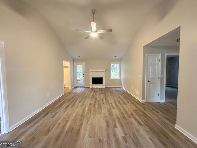 unfurnished living room featuring ceiling fan, light hardwood / wood-style floors, a fireplace, and vaulted ceiling