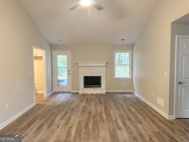 unfurnished living room with a fireplace, light hardwood / wood-style flooring, vaulted ceiling, and a wealth of natural light