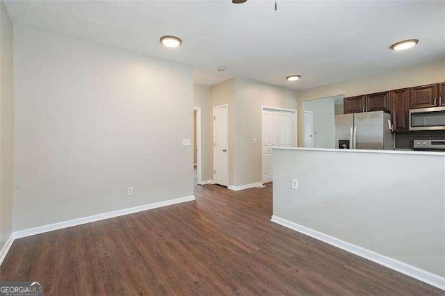 kitchen with decorative backsplash, dark brown cabinets, dark wood-type flooring, and appliances with stainless steel finishes