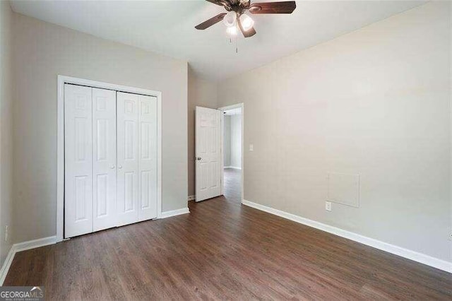 unfurnished bedroom with ceiling fan, a closet, and dark wood-type flooring