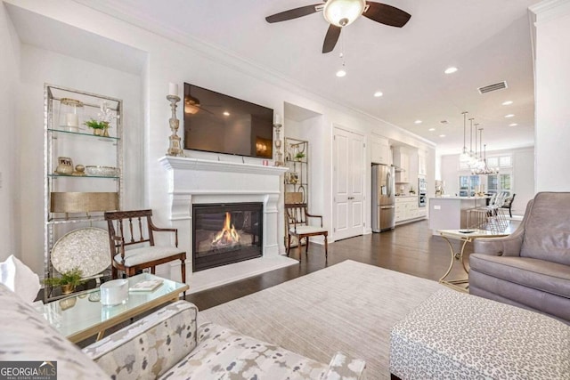 living room with ceiling fan, dark wood-type flooring, and ornamental molding