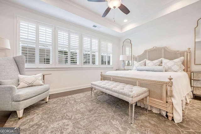 bedroom featuring hardwood / wood-style flooring, a raised ceiling, ceiling fan, and crown molding