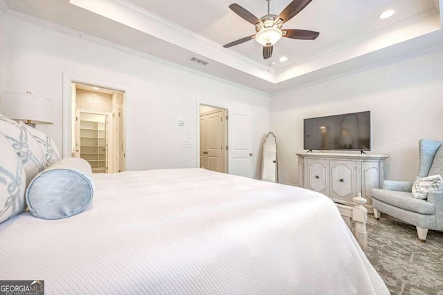 carpeted bedroom featuring a tray ceiling, ceiling fan, a closet, and ornamental molding