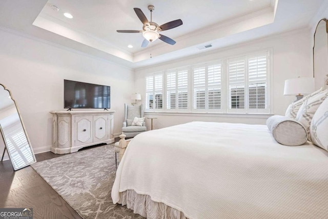 bedroom with a raised ceiling, ceiling fan, wood-type flooring, and ornamental molding