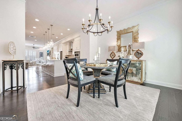 dining area with dark wood-type flooring, ceiling fan with notable chandelier, and ornamental molding