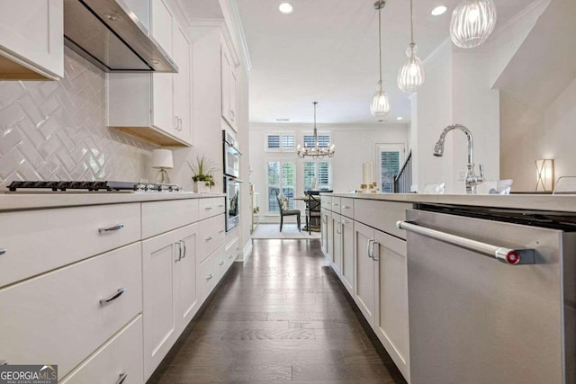 kitchen featuring stainless steel appliances, dark hardwood / wood-style flooring, decorative light fixtures, white cabinets, and ornamental molding