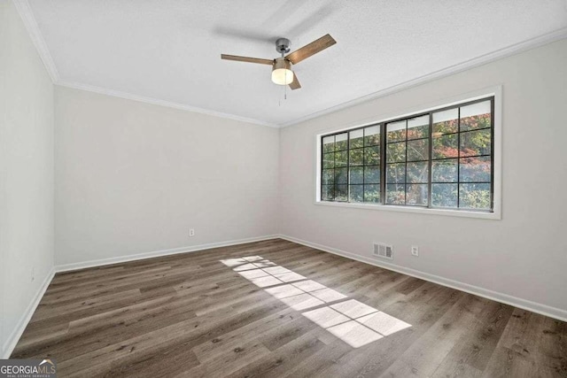 empty room with ceiling fan, dark hardwood / wood-style floors, and ornamental molding