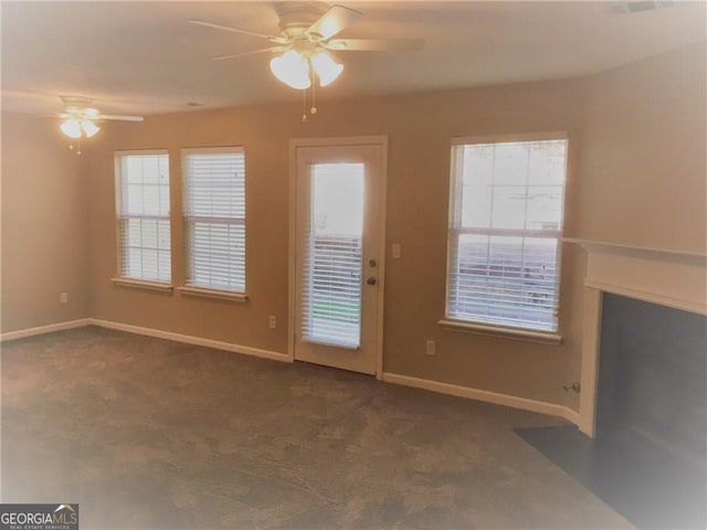 unfurnished living room featuring ceiling fan and dark colored carpet