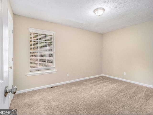 carpeted spare room with a textured ceiling