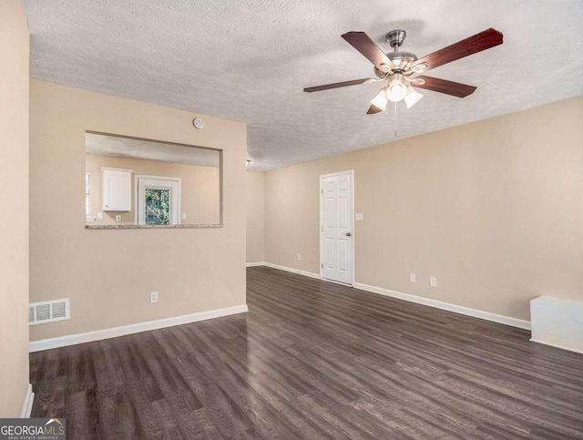 empty room featuring ceiling fan, dark wood-type flooring, and a textured ceiling