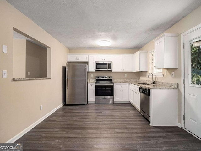 2887 Rockcliff Rd SE, Atlanta, GA 30316 - kitchen with stainless steel appliances, a sink, white cabinets, dark wood-style floors, and a textured ceiling