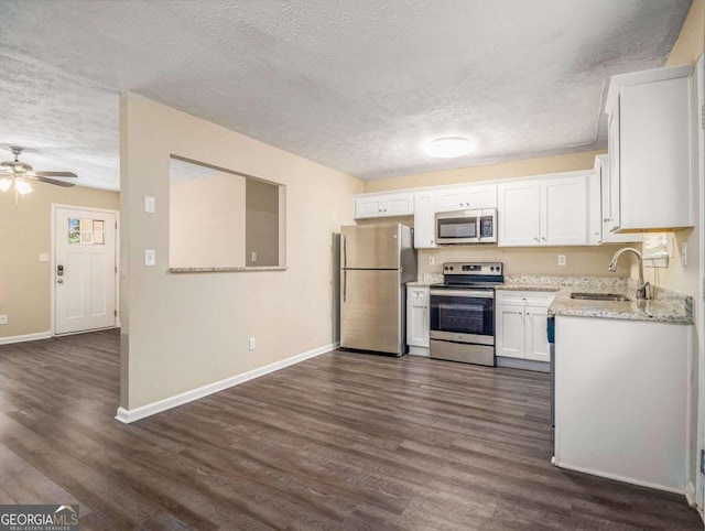 kitchen with dark wood-type flooring, white cabinets, sink, a textured ceiling, and stainless steel appliances