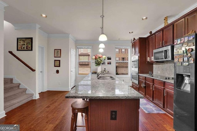 kitchen featuring light stone countertops, dark wood-type flooring, crown molding, pendant lighting, and black appliances