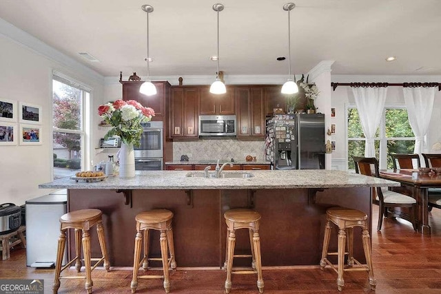 kitchen featuring decorative light fixtures, a kitchen bar, dark wood-type flooring, and appliances with stainless steel finishes