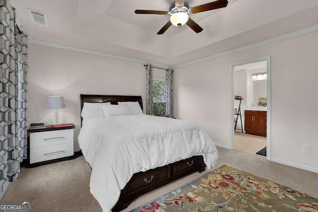 bedroom featuring ensuite bath, ceiling fan, a tray ceiling, light carpet, and ornamental molding