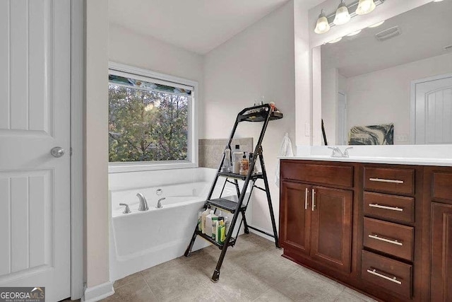 bathroom with tile patterned floors, a bathing tub, and vanity