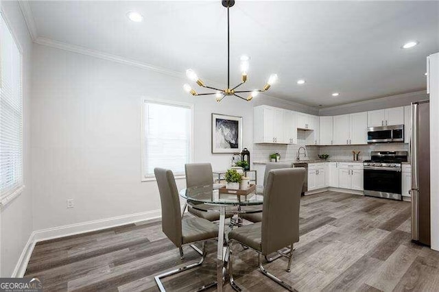 dining room featuring a wealth of natural light, crown molding, wood-type flooring, and a notable chandelier