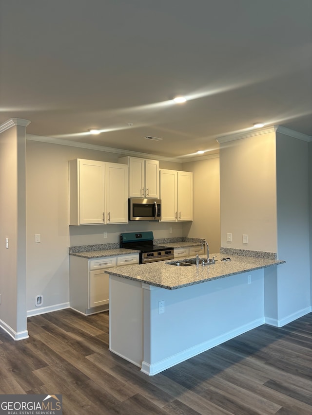 kitchen with kitchen peninsula, appliances with stainless steel finishes, white cabinetry, and dark wood-type flooring