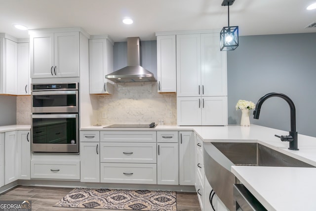 kitchen with pendant lighting, white cabinets, wall chimney range hood, dark hardwood / wood-style floors, and stainless steel appliances