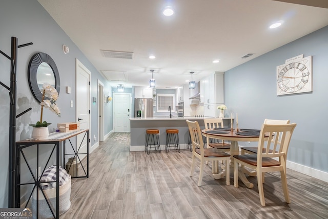 dining space with sink and light wood-type flooring