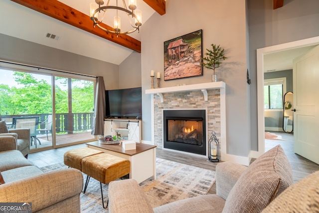 living room featuring high vaulted ceiling, light wood-type flooring, a fireplace, beam ceiling, and a chandelier