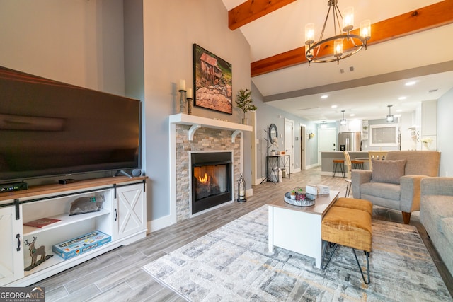 living room featuring a stone fireplace, lofted ceiling with beams, light hardwood / wood-style floors, and a notable chandelier