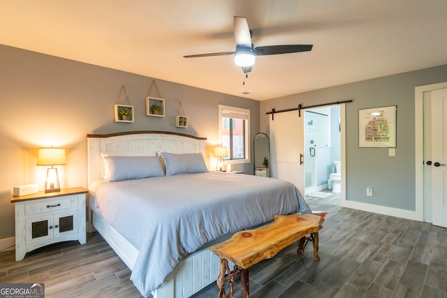 bedroom with hardwood / wood-style flooring, ceiling fan, a barn door, and ensuite bath