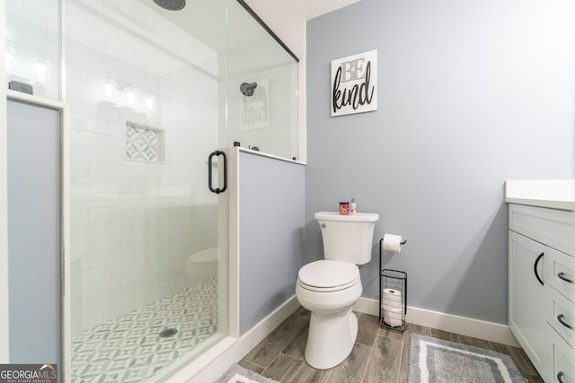 bathroom featuring vanity, hardwood / wood-style flooring, toilet, and a shower with shower door