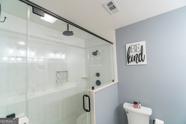 bathroom featuring a textured ceiling, an enclosed shower, and toilet