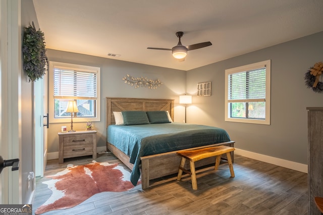 bedroom featuring dark hardwood / wood-style floors, multiple windows, and ceiling fan