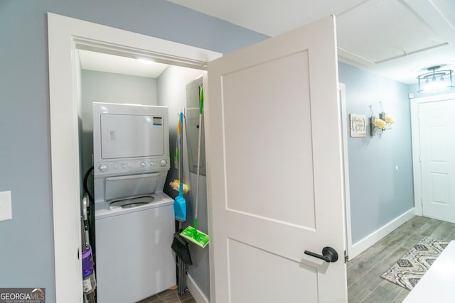 washroom with wood-type flooring and stacked washing maching and dryer