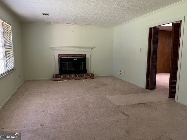 unfurnished living room with light carpet, a textured ceiling, a brick fireplace, and crown molding