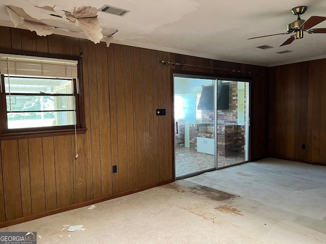 empty room featuring ceiling fan, light carpet, and wooden walls