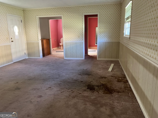 carpeted spare room featuring crown molding and wooden walls