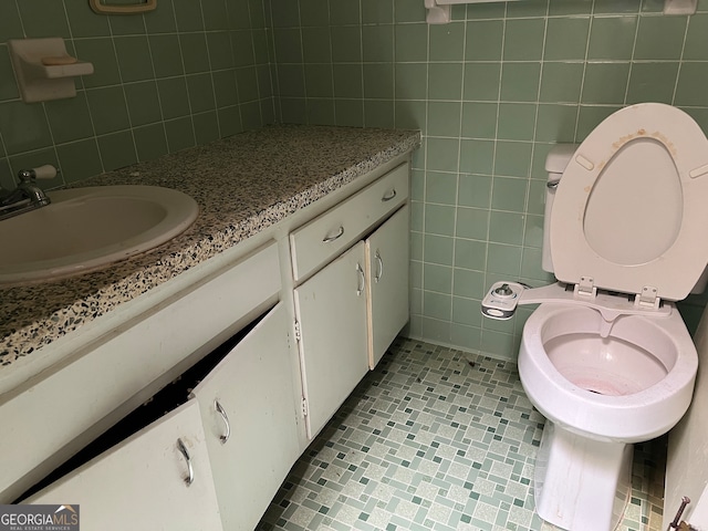 bathroom with vanity, toilet, and tile walls