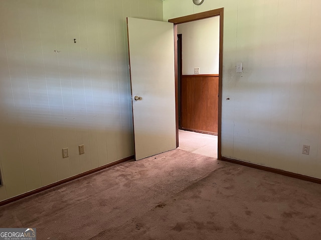 carpeted spare room with wooden walls