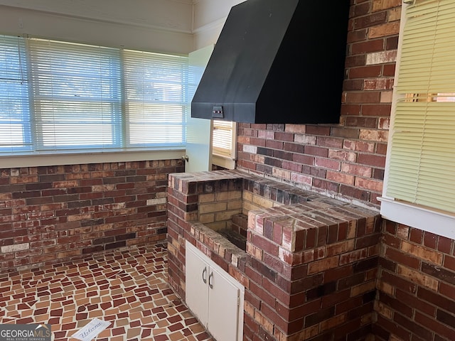 kitchen with exhaust hood and brick wall