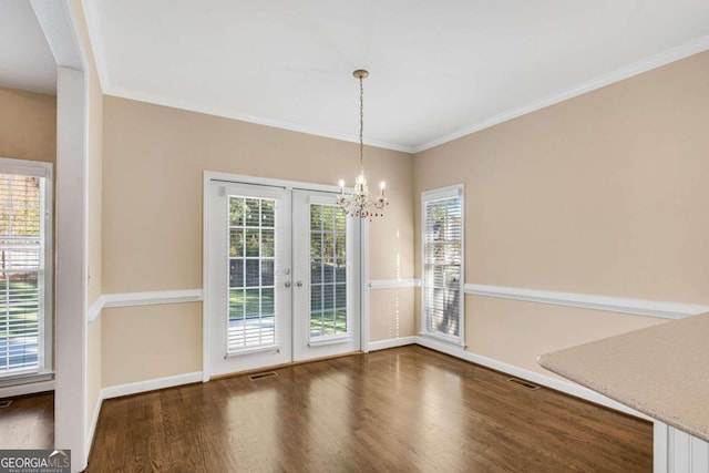 unfurnished dining area with an inviting chandelier, dark hardwood / wood-style flooring, ornamental molding, and french doors