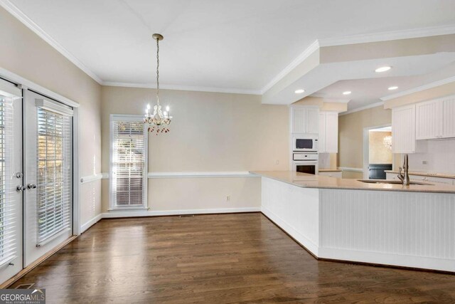 kitchen featuring white appliances, crown molding, dark wood-type flooring, sink, and pendant lighting