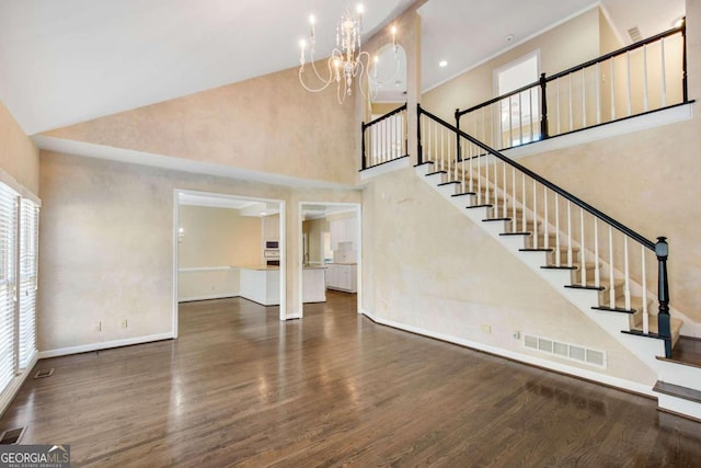 stairway with hardwood / wood-style floors, a notable chandelier, and a high ceiling