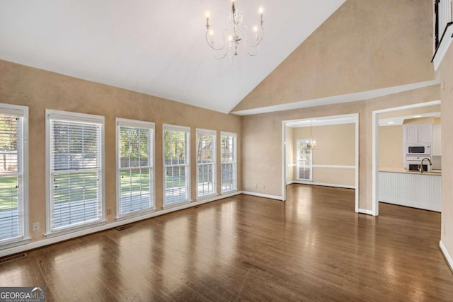 unfurnished living room featuring dark hardwood / wood-style flooring, sink, high vaulted ceiling, and an inviting chandelier