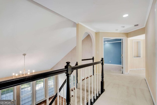 hall featuring a chandelier, light colored carpet, and crown molding