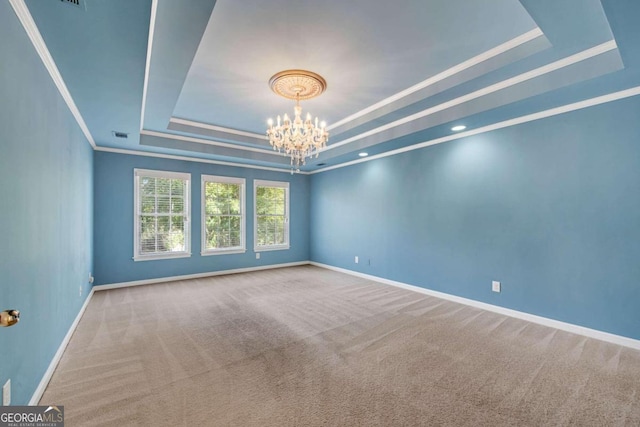 carpeted empty room with a raised ceiling, crown molding, and a notable chandelier