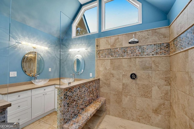 bathroom featuring vanity, tiled shower, and vaulted ceiling