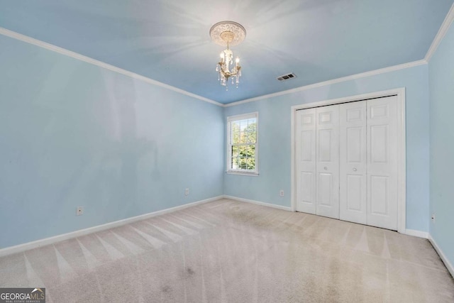 unfurnished bedroom featuring a chandelier, light colored carpet, crown molding, and a closet