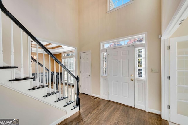 entrance foyer featuring a skylight, dark hardwood / wood-style flooring, and a towering ceiling