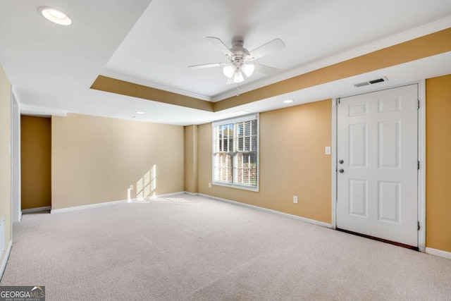 carpeted empty room featuring a raised ceiling, crown molding, and ceiling fan