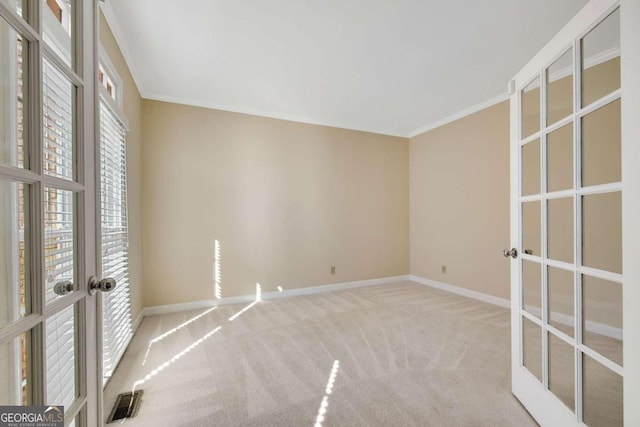 empty room with ornamental molding, light carpet, and french doors