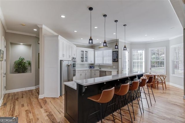 kitchen featuring white cabinetry, stainless steel appliances, light hardwood / wood-style floors, decorative light fixtures, and ornamental molding